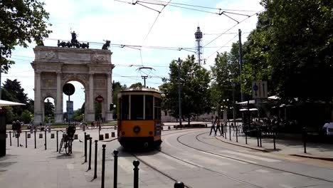 Urban-scene-of-old-yellow-tram-running-on-tramway-tracks-in-Milan-city-at-Arco-della-Pace-or-Arch-of-Peace-in-Italy