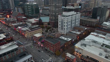 Aerial-view-of-the-Broadway-street-and-architecture-of-downtown-Nashville,-dusk-in-Tennessee,-USA---rising,-drone-shot