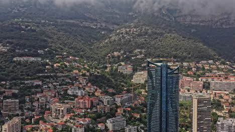 Monaco-Aerial-v20-drone-fly-around-tallest-building-in-the-city,-tower-odeon-a-double-skyscraper,-capturing-its-surrounding-cityscape-and-beautiful-mediterranean-seascape---July-2021