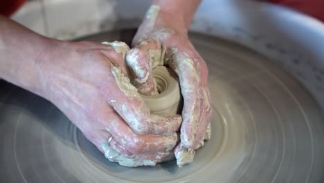 Clay-jar-being-sculpted-on-a-potters-wheel-by-female-hands,-Close-up-view