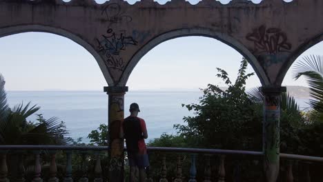 Young-male-tourist-looking-over-the-seaside-town-of-Jaco-from-El-Miro,-an-old-abandoned-hotel-in-Costa-Rica