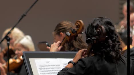Focus-on-young-female-musicians-playing-the-cello-with-an-orchestra,-Liepāja-Symphony-Orchestra-season-opening-concert,-concert-hall-Great-Amber-,-medium-shot,-rack-focus