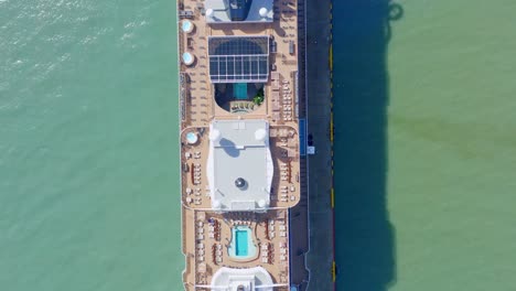 Aerial-top-down-forward-over-luxury-cruise-ship-moored-in-port-of-Taino-bay,-Puerto-Plata-in-Dominican-Republic