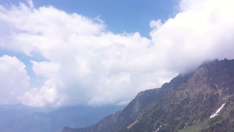Toma-Aérea-De-ángulo-Bajo-De-Nubes-Que-Cubren-El-Pico-De-Una-Montaña-En-Manali-India