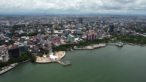 Vista-Aérea-De-Grandes-Edificios-En-La-Ciudad-De-Makassar-Sulawesi-Indonesia-En-Un-Día-Soleado-A-Lo-Largo-Del-Agua