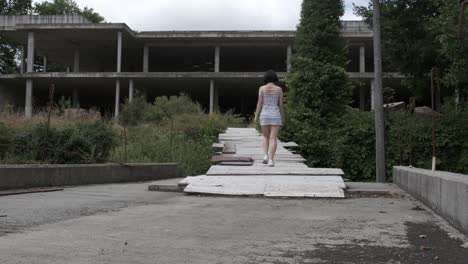 Unrecognizable-woman-enters-abandoned-water-park.-Static-view