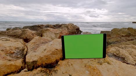 Modernes-Tablet-Touchpad,-Das-Auf-Felsen-Lehnt,-Mit-Meer-Im-Hintergrund