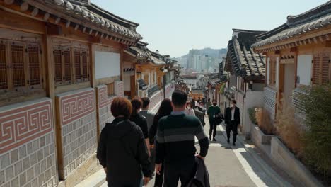 Groups-of-people-visiting-Bukchon-Hanok-Village-in-Seoul,-South-Korea---Panning-across-the-street