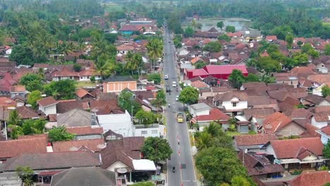 Buildings-and-trafficked-road-in-Mungkid-in-Indonesia,-forward-aerial