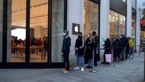 People-wearing-facemasks-lining-up-in-front-of-Apple-Store-in-Winter