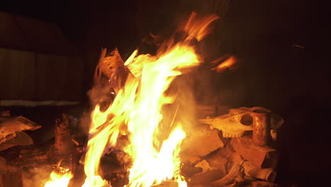 Hunter's-Fire-at-Night,-Tracking-Slider-Shot,-Deer-Skulls-Drying-in-Background