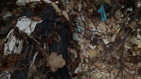old-fabrics-and-plastic-wastes-pollute-the-forest,-slow-motion-close-up-shot