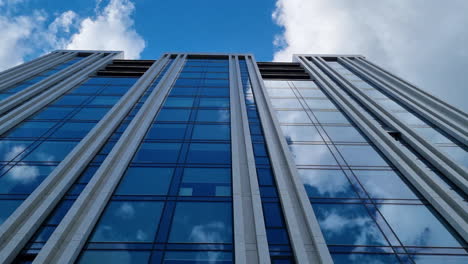 Blue-sky-and-clouds-reflect-in-the-windows-of-the-modern-business-glass-building