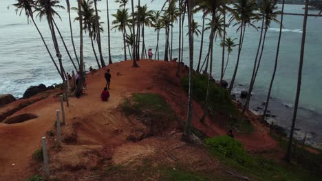 Aerial-view-of-a-group-of-people-on-coconut-hill-in-Sri-Lanka,-Rise-Up-Shot