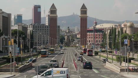 Fahrzeuge-Fahren-Auf-Der-Straße-Mit-Torres-Venezianes-Und-Placa-D&#39;Espanya-Im-Hintergrund-In-Barcelona,-Spanien
