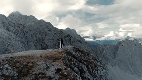 Aerial-orbit-of-a-couple-on-mountain-peak-of-the-panoramic-mountaing-range-alps-with-a-sky-full-of-clouds---cinematic-landscape-drone-shot