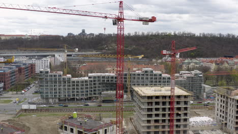 Red-tower-cranes-at-construction-site-in-Prague,-pedestal-drone-shot