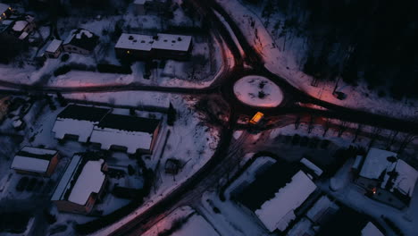 Truck-drives-by-roundabout-in-rural-wintertime-Finland,-aerial-pan