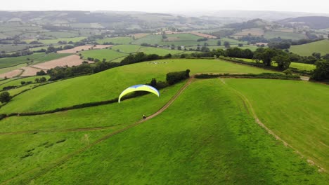 Parallax-shot-of-a-paraglider-flying-over-the-East-Devon-Countryside-England