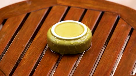 Upside-Yellow-Ceramic-Ashtray-on-a-Wooden-Table-Outdoors-with-Pouring-Rain-in-the-Garden