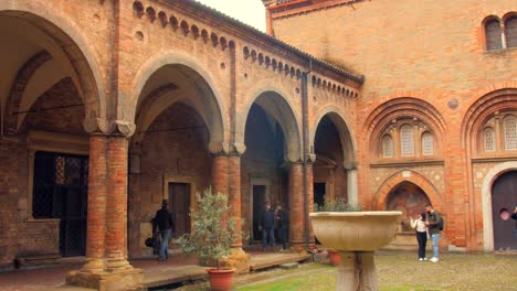 Pan-shot-of-Basilica-of-Santo-Stefano-also-called-the-Seven-Churches-and-the-cloister-with-columns-and-brick-wall-in-Bologna,-Italy,-Europe