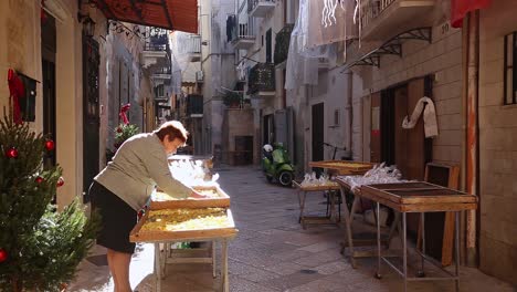 Woman-selling-products-on-a-narrow-street-in-Bari,-Italy