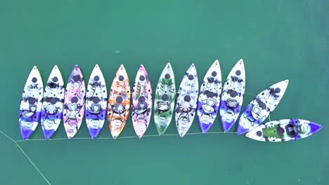 A-dynamic-top-down-aerial-shot-of-colorful-kayaks-or-small-watercrafts-that-are-tied-up-neatly-and-ready-to-be-rented-by-tourists