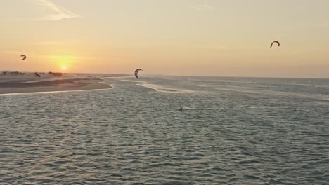 Drohnenverfolgung-Von-Guriu-Kitesurfern,-Die-Im-Sonnenuntergang-Am-Meereshorizont-Spielen