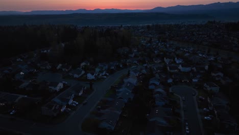Aerial-of-a-neighborhood-still-asleep,-tilting-up-to-reveal-the-sunrise-over-the-Cascade-Mountains