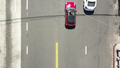 Red-Mini-Cooper-drives-into-the-frame-and-is-followed-by-the-camera-Smooth-aerial-view-flight-bird's-eye-view-drone-footage-in-LA-at-Venice-Beach-USA-2018