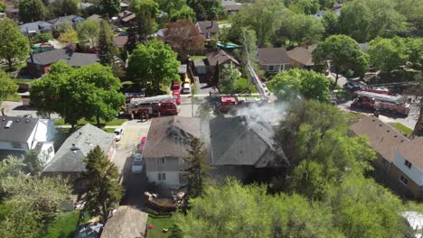 Luftaufnahme-Von-Feuerwehrfahrzeugen,-Die-In-Einem-Vorort-Von-Toronto-Hausbrände-Auslösen-Wollen,-Wobei-Rauch-Vom-Dach-Aufsteigt
