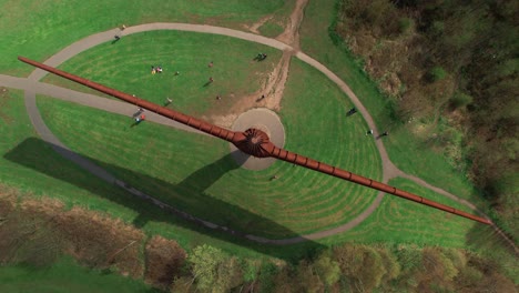 Drone-Orbitando-Arriba,-Acercándose-Hacia-La-Famosa-Escultura-Del-ángel-Del-Norte-En-Gateshead,-Reino-Unido-Con-Gente-En-El-Suelo