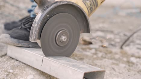 Worker-cutting-metal-with-electric-circular-saw-outdoors-on-construction-site,slow-motion