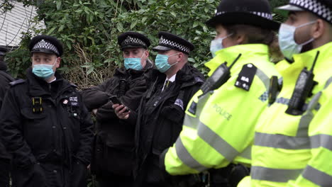 A-group-of-Metropolitan-police-officers-wearing-protective-surgical-face-masks-stand-watching-as-a-protest-gathers-during-the-Covid-pandemic