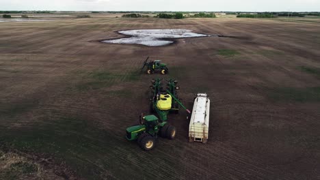 Flyover-drone-shot-of-farmers-preparing-to-seed-a-field