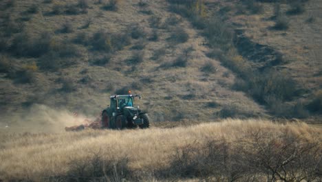 Rule-of-thirds-telephoto-view-of-a-tractor-plowing-on-a-field-on-a-warm-sunny-day-with-a-hill-in-the-background