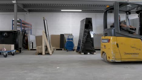 Solar-panel-warehouse-with-forklift-moving-a-set-of-cells-in-a-crate-for-shipment,-Dolly-in-reveal-shot