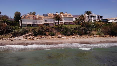 Aerial-View-Of-Sea-Waves-Breaking-On-Beach-With-View-Of-Holiday-Villas-In-Estepona,-Costa-del-Sol
