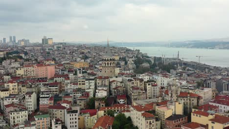 Aerial-drone-circling-Galata-Tower-in-Taksim-Istanbul-Turkey-on-a-cloudy-day-overlooking-old-European-residential-buildings-and-the-Bosphorus-River