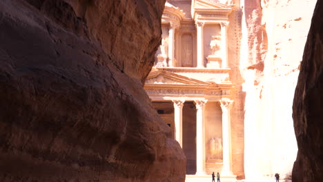 Walking-through-the-siq-Canyon-in-Petra-Jordan,-revealing-the-Treasury-Al-Khazneh-most-elaborate-sandstone-carved-temples