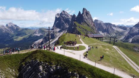 Seceda-at-Urtijei,-South-Tyrol,-Italian-Alps,-Dolomites,-Italy---Aerial-Drone-View-of-Jesus-Statue,-tourists-and-Mountain-Peak