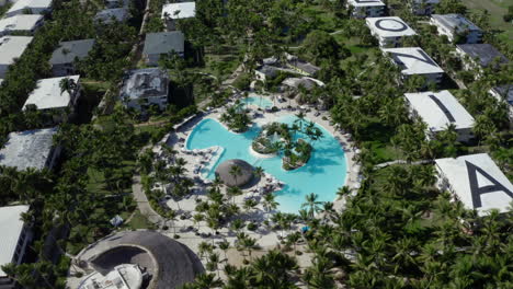 Luxurious-hotel-resort-swimming-pool-with-palm-trees,-drone-shot
