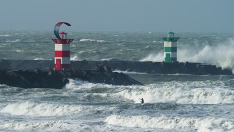 Mutiger-Kitesurfer-Reitet-Auf-Großen-Stürmischen-Wellen,-Die-Heftig-In-Den-Pier-Krachen-Und-Sprühen