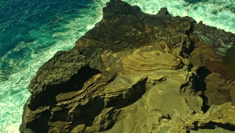 Overhead-view-of-waves-splashing-over-volcanic-rock-formation-on-Oahu