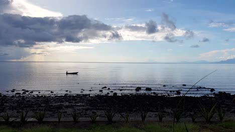 Ein-Alleinstehender-Fischer-Auf-Einem-Traditionellen-Hölzernen-Fischerkanu,-Der-Im-Frühen-Morgenlicht-Auf-Der-Insel-Atauro,-Timor-Leste,-Durch-Das-Meer-Paddelt