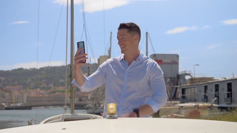 a-young-Caucasian-man-on-his-little-boat-who-picks-up-his-phone-to-do-a-live-video-call