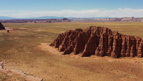 Eine-Wunderschöne-Luftdrohnenaufnahme-Einer-Atemberaubenden-Wüstenszene-Mit-Orangefarbenem-Sand-Und-Großen-Roten-Felsformationen-In-Utah