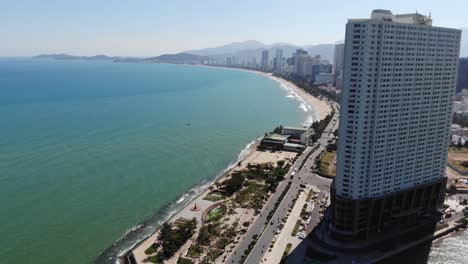 Aerial-view-of-tall-hotel-building-and-seaside-with-Nha-Trang-cityscape-during-beautiful-summer-sunny-day-in-Vietnam