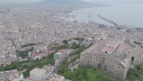Wide-aerial-video-of-Castel-Sant'Elmo-panning-up-to-revealing-Mount-Vesuvius-and-the-harbor-in-Naples,-Italy
