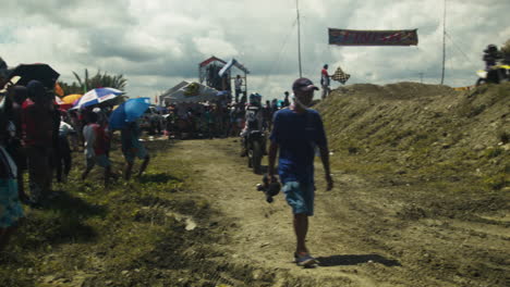 Onlookers,-participants,-and-the-media-pass-by-near-the-race-track-as-the-highly-anticipated-motocross-competition-is-about-to-begin